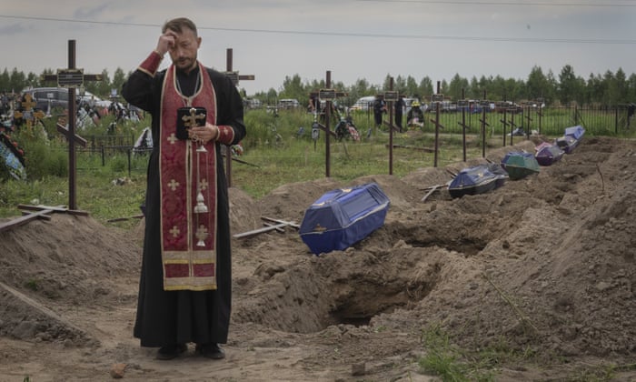 A priest prays for unidentified civilians killed by Russian troops in Bucha.
