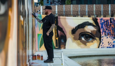 A man paints a mural on a wall