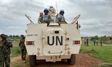 A white UN armoured vehicle passes UN soldiers in fatigues