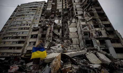 A woman with a Ukrainian flag inspects a destroyed residential building in Kharkiv.