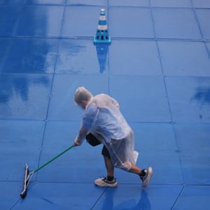A worker during rainy weather prepares the track for the women’s triathlon at the Tokyo Olympics.