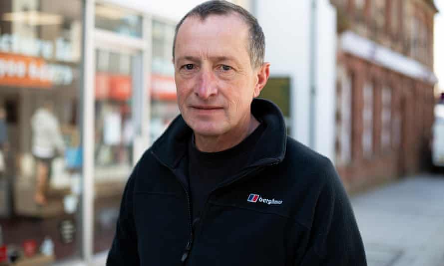 Man standing in street wearing dark jacket. Background is in soft focus