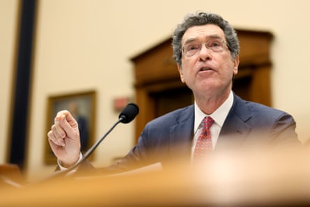 a man in a suit speaks into a microphone while seated