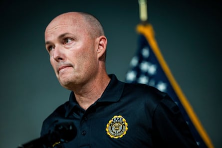 A bald man in front of a US flag.