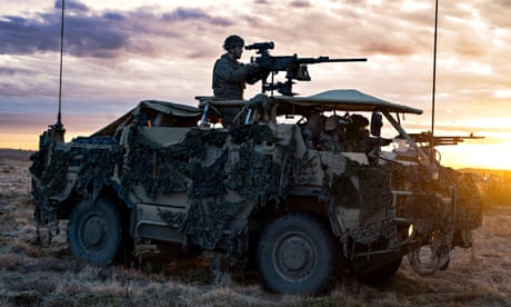 Một người lính đứng cạnh vũ khí gắn trên xe bọc thép