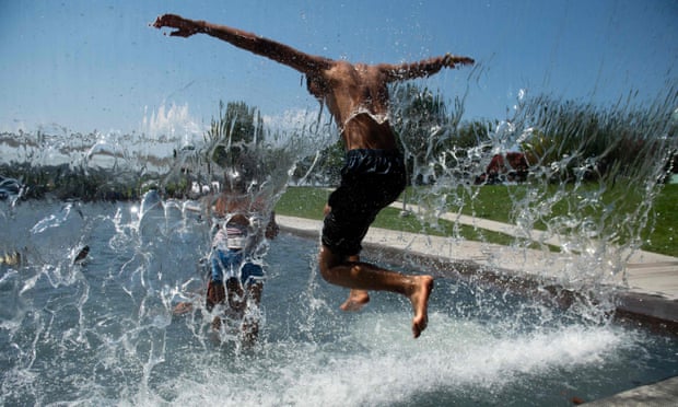 People play in a waterfall at Yards Park in Washington DC. Temperatures in the capital were set to reach 100F this weekend.