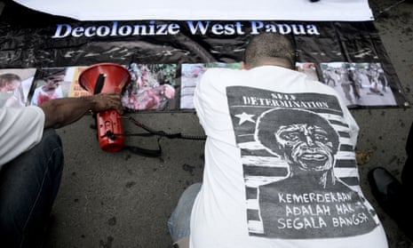 An Indonesian activist kneels before West Papuan pro-independence demonstrators.