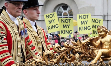 A coach carrying royals rides past protesters following the coronation ceremony of King Charles III