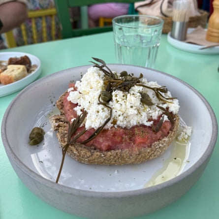A plate with brown bread topped with tomato, olive oil and mizithra cheese