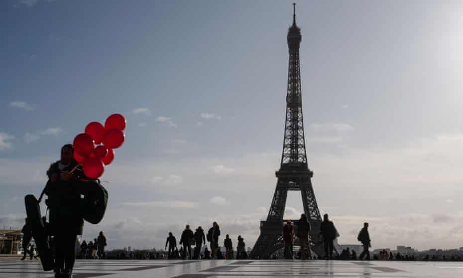 A woman holds red balloons on the Trocadero Plaza, in front of the Tour Eiffel