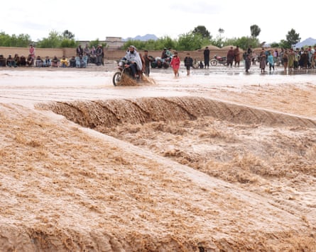 A motorcyclist rides across a flooded road at Zawul district in Herat province as others wade through the water