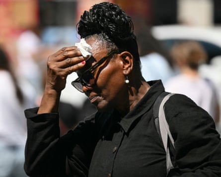 A woman wipes sweat from her face as she walks through Midtown Manhattan during a heatwave in New York.