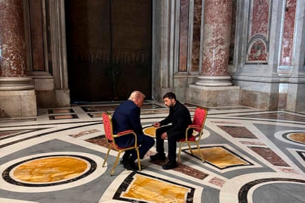 Donald Trump and Volodymyr Zelenskyy sitting on chairs in the centre of a grand marbled floor in a deep discussion