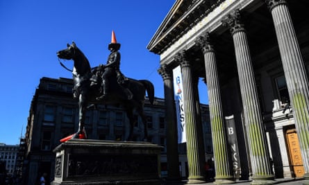 A statue of the Duke of Wellington riding a horse beside the columns at the entrance to the Gallery of Modern Art. The statue has a traffic cone on its head