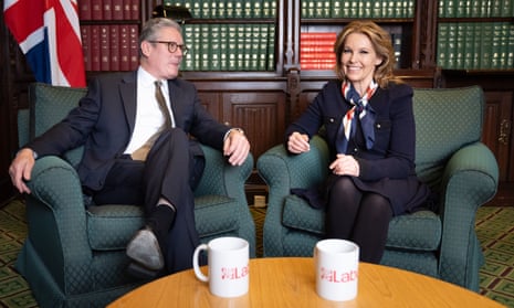 Keir Starmer and Natalie Elphicke sit in front of a packed bookcase in his office. A coffee table with two Labour mugs is in the foreground and there is a union flag behind them.