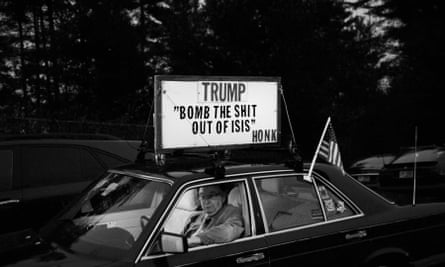 A man sits in a car with a sign on top outside a political event where Republican Presidential candidate Donald Trump is due to speak.