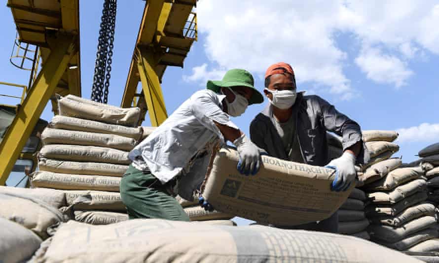 Bags of cement are loaded on a barge at a dock on the Red River in Hanoi, Vietnam.