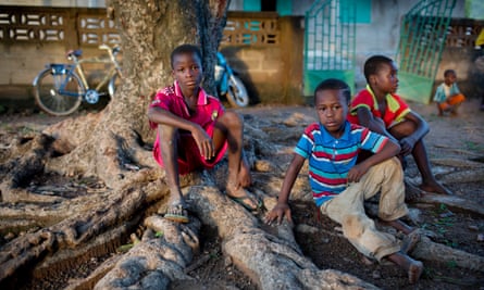 Children sit outside a clinic in a community near Doko, Siguiri, in northern Guinea
