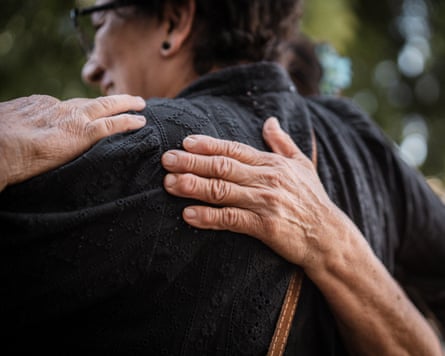 Indistinguishable people embrace and pat each other on the back.