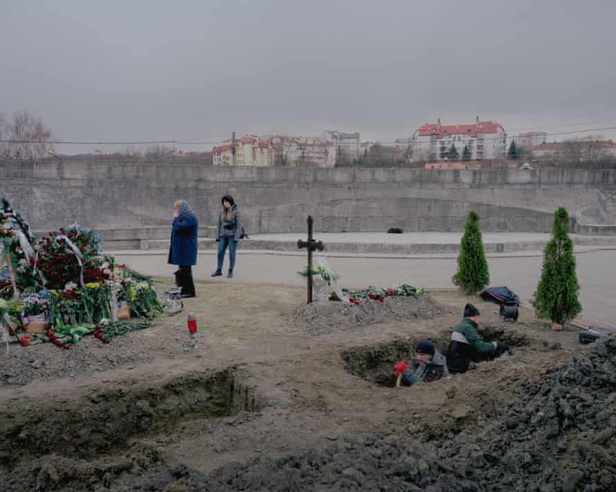 New graves for soldiers are dug while people mourn at Lychakiv cemetery in Lviv, 10 March