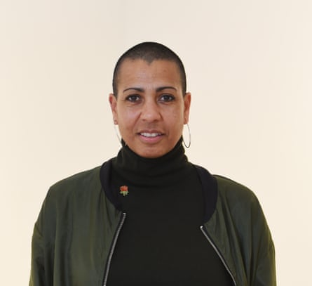 A woman with short hair wearing a black top and dark jacket starring directly at the camera with a slight smile on her face.