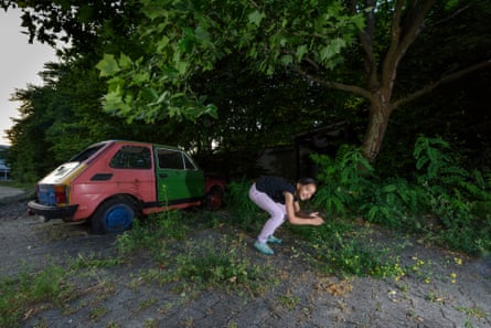 Slavica, Stanko’s sister, pretends to be a jumping fox next to an abandoned car in Spandau.