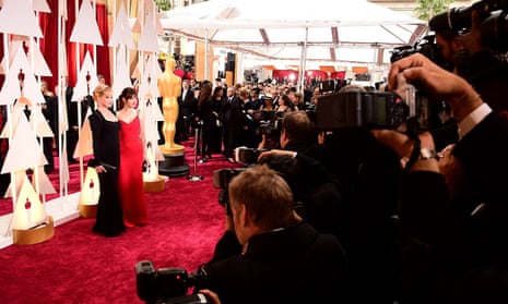 pair pose on red carpet as photographers take pictures