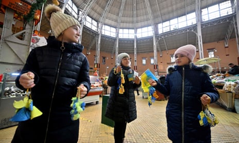 A woman and her daughters sell souvenirs to donate money to Ukrainian army ahead of the New Year's Eve celebrations in the center of the Ukrainian capital of Kyiv.