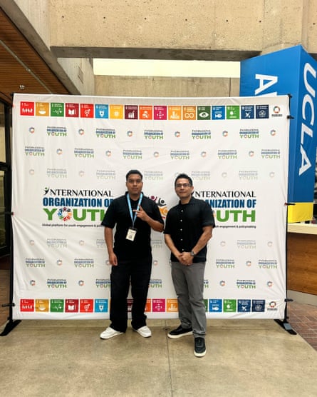 Two men stand in front of a backdrop