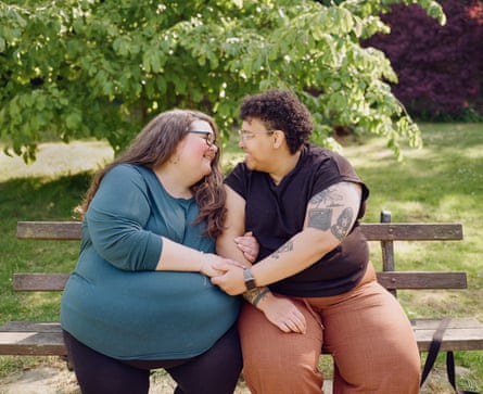Gemma and Lizzie sitting on a bench holding hands and smiling at each other