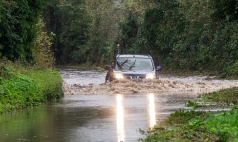 A driver hangs his arm into the water near the village of Alfriston, East Sussex where the River Uck has burst its banks due to persistent heavy rain.