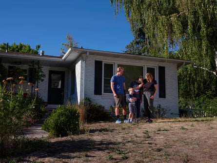 A woman and her children in front of their home