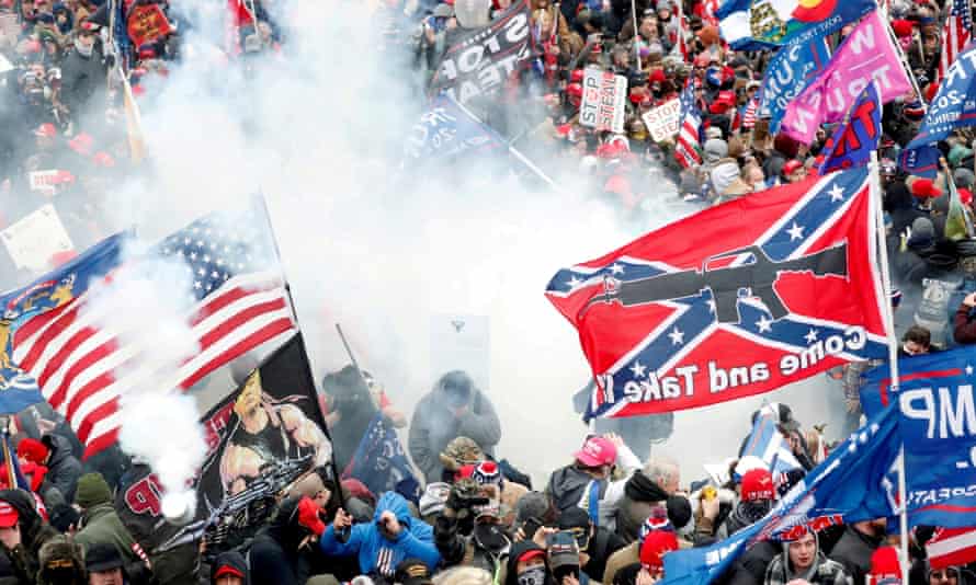 Tear gas is released into a crowd of protesters, with one wielding a Confederate battle flag, at the US Capitol on 6 January 2021.