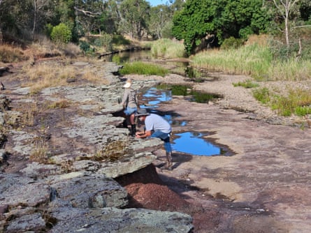 Two people inspecting rocky creek bed