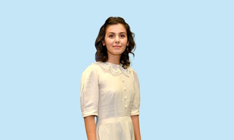 Katie Melua in a cream dress with a lace collar, standing in front of a pale blue backdrop