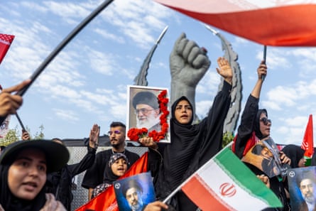 People hold up images of Khamenei and Iranian national flags in Revolution Square