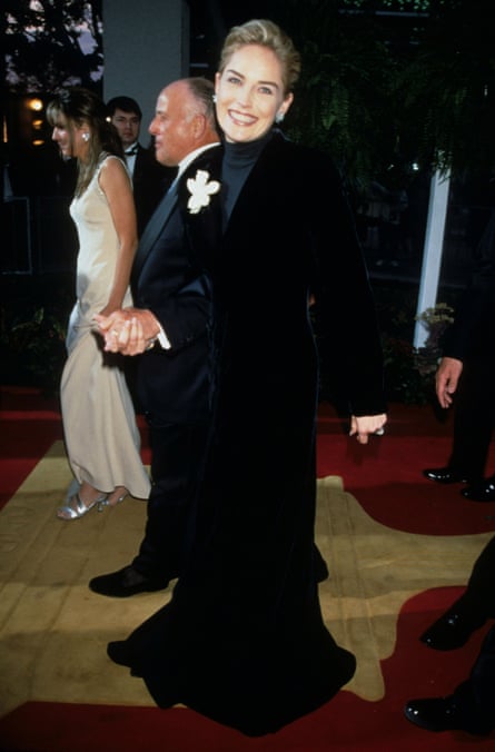 Sharon Stone long black velvet gown or coat-style dress with a high-neck (turtleneck-like) top underneath.