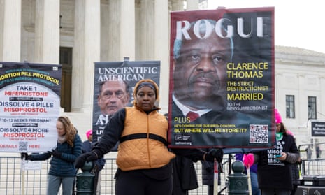 A person holds up a sign criticizing Associate Justice Clarence Thomas, as abortion-rights and anti-abortion activists rally outside the supreme court in March 2024.