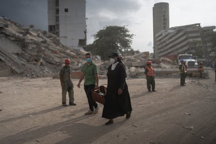 A nun walks in front of the wreckage of a building