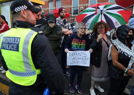 Woman holding a ‘Nans against Nazis’ sign next to a police officer.