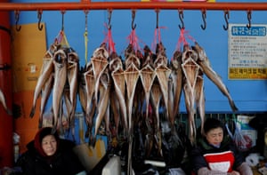 Street vendors selling dried fish wait for customers at a local market in Gangneung.