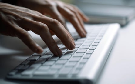Hands typing on a keyboard in an office.