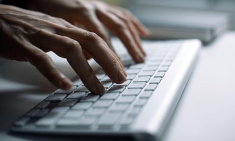 A woman’s hands are seen typing on a keyboard in an office.