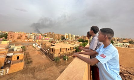 People watch as smoke rises during clashes between the army and the RSF in Omdurman on 4 July.