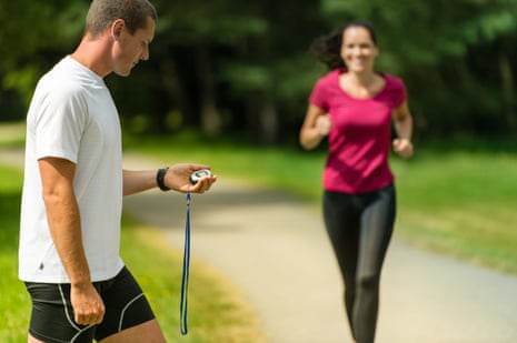 Portrait of male coach timing a female runner outdoors