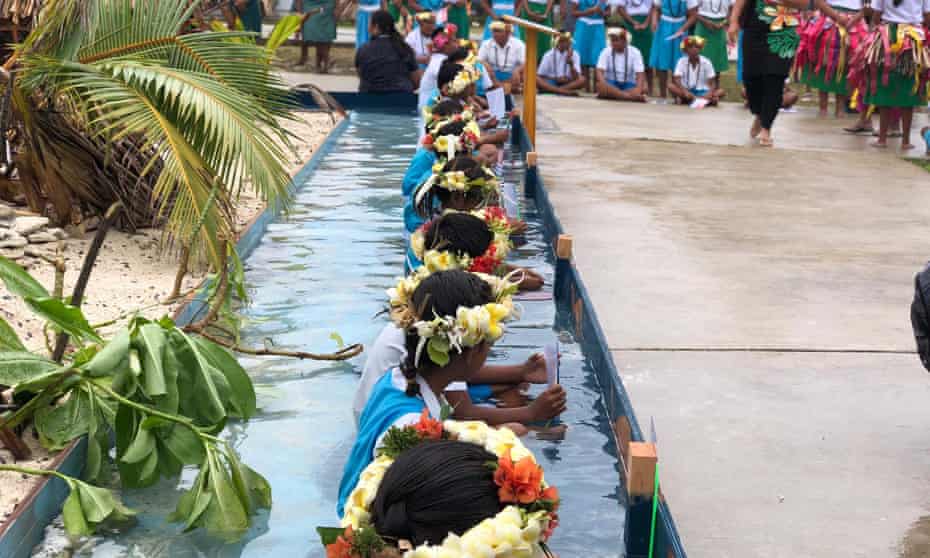 Children from Tuvalu sit in a moat of water