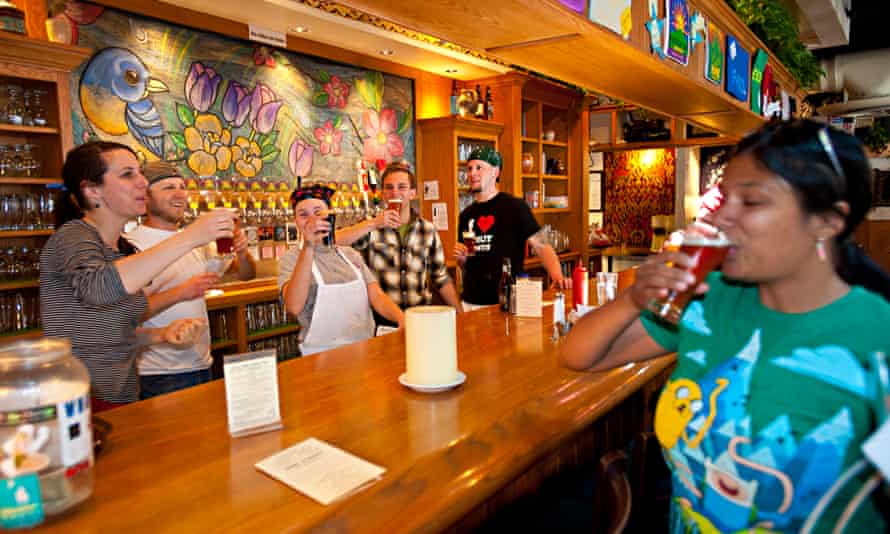 Bar staff and a female customer, sipping a beer, at Vine Street Brewery, Denver, Colorado, US.