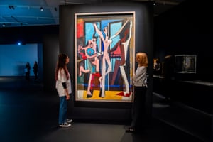 Two women stand either side of a large and colourful painting