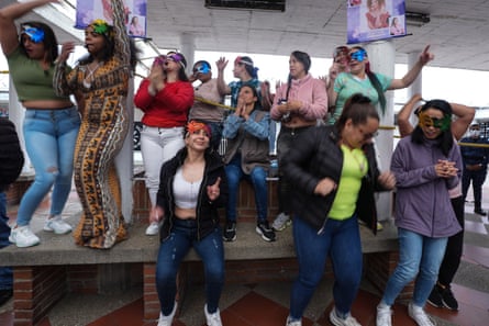 A group of women, most wearing colourful masks, are dancing