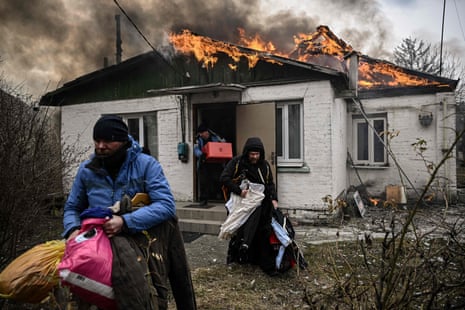 People remove personal belongings from a burning house after being shelled in the city of Irpin 